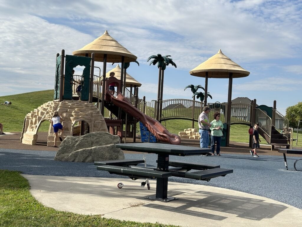 Picnic table plus a playground that is supposed to look like an island at a park with a rubber ground