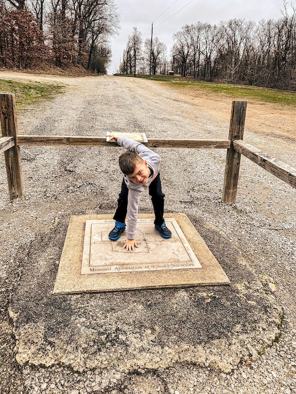 Boy standing in the Tri-state Marker near Joplin, Missouri where Oklahoma, Kansas, and Missouri meet.