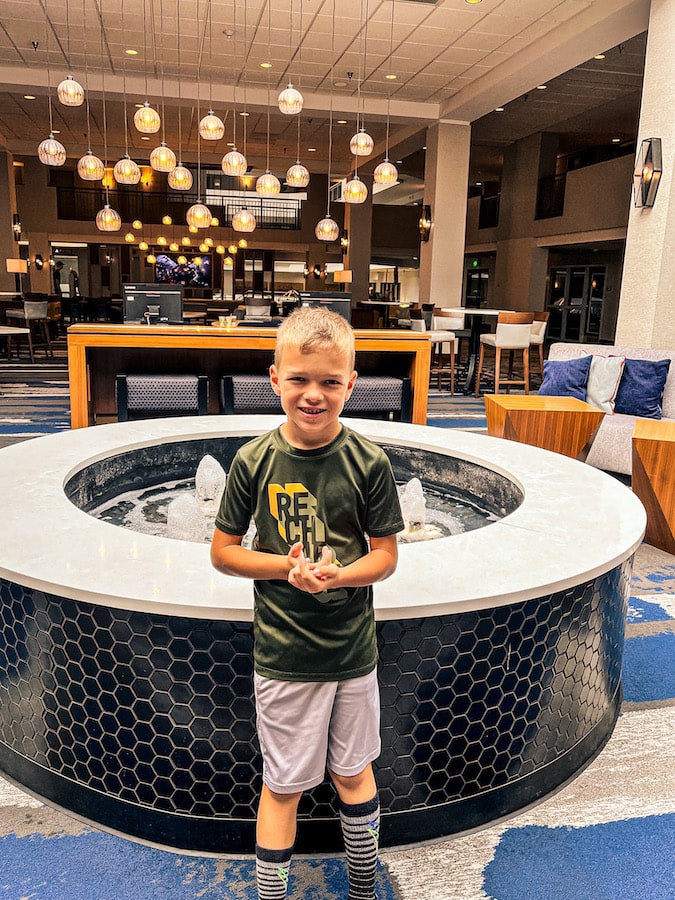 Boy standing in front of a fountain in the Embassy Suites lobby