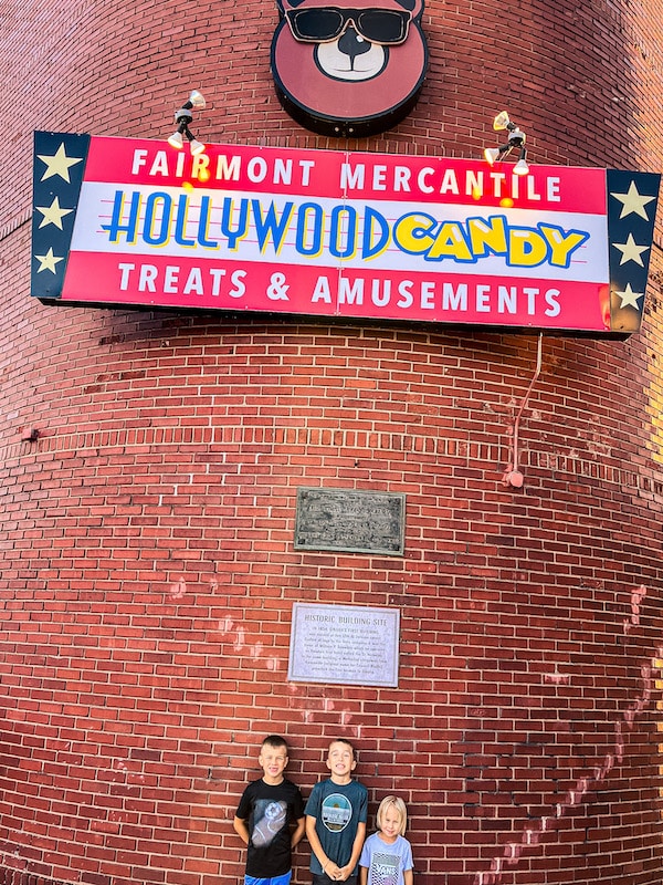 Three boys standing in front of brick building for Fairmont Mercantile Treats and Amusements