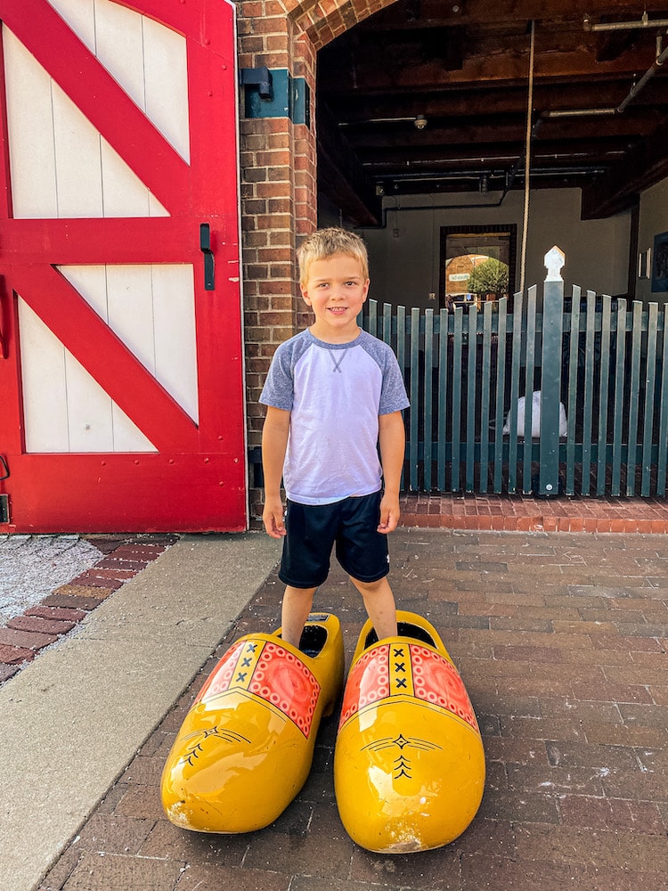 Boy standing in a pair of large wooden yellow Dutch shoes