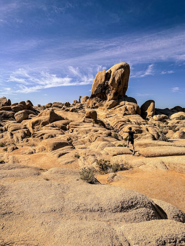 Boy hiking on large boulders in the desert with blue sky in the background