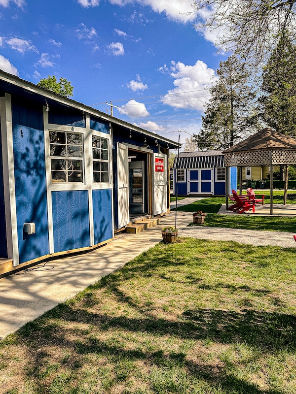 Blue small building with windows and door with a red sign that says Check In