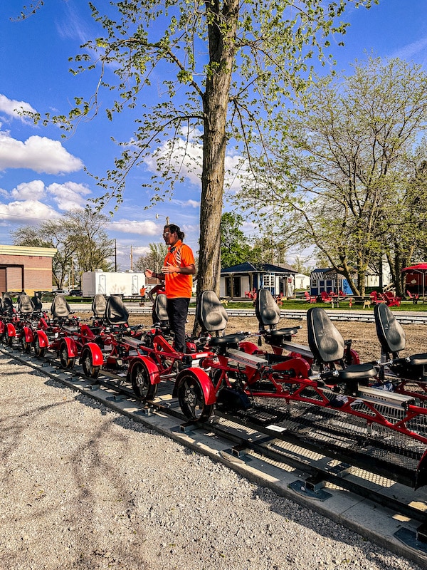 Man standing and giving directions amongst a bunch of red rail bikes