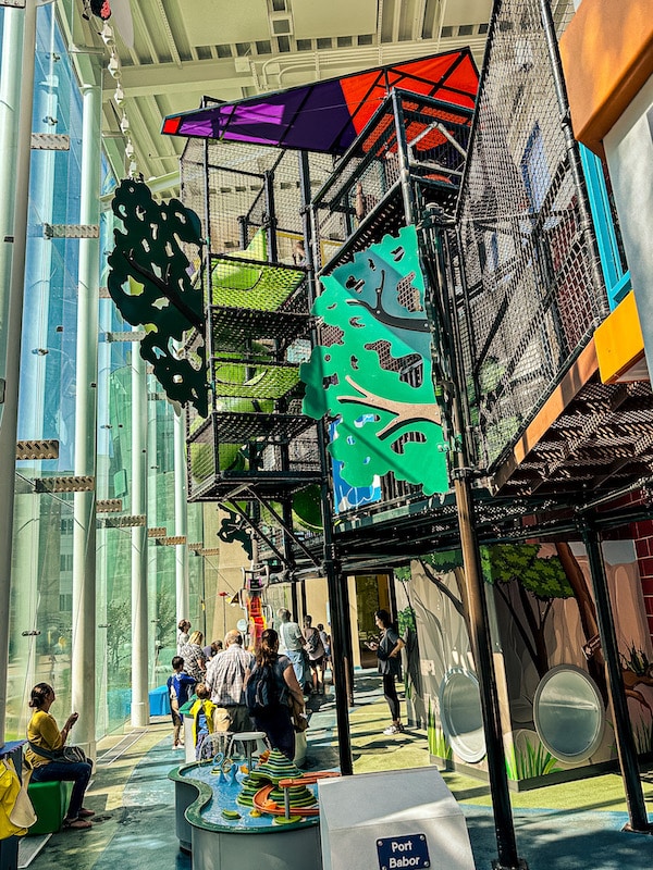2 story colorful play and climbing structure inside of a Children's Museum with tons of windows