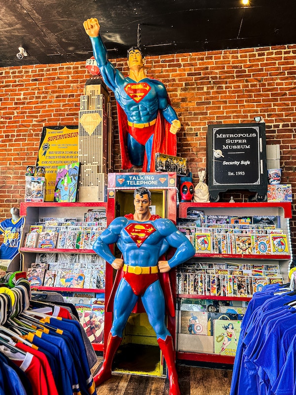 Inside of a store with comics and a superman statue and superman cut-out