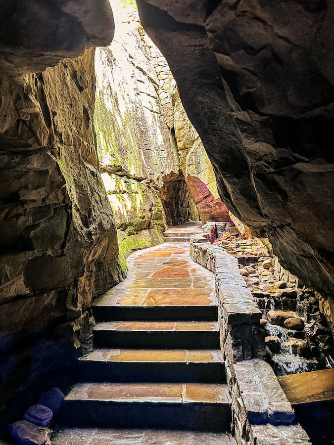 Stone steps and pathway through a short tunnel and tall rock walls