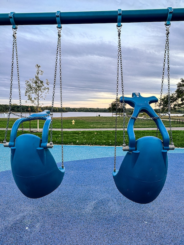 Two all inclusive swings facing the lake at Raccoon River Park.