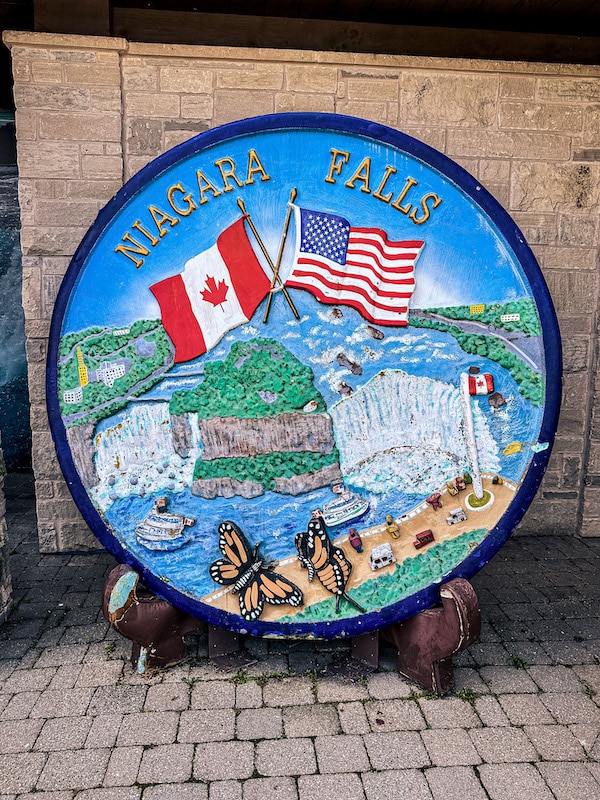 Large circle or plate with Niagara Falls on it as well as the Canadian and American flags.