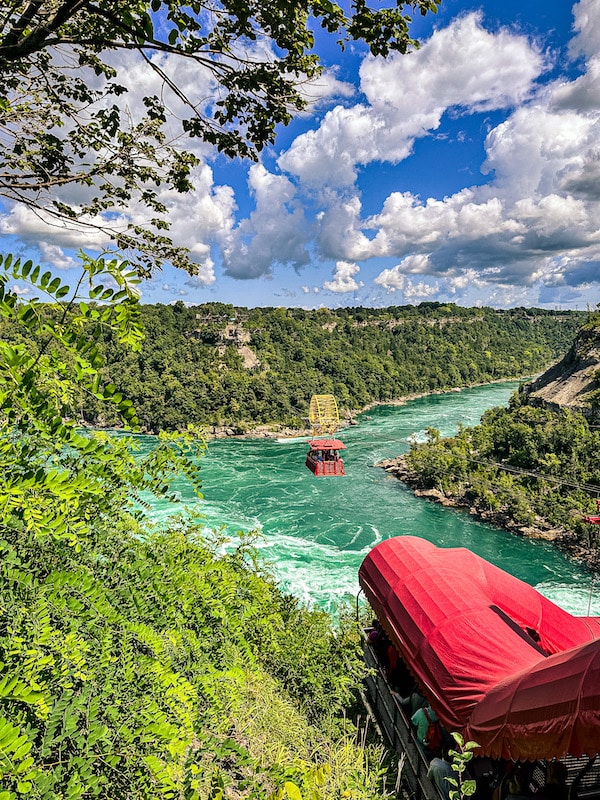 View of the red whirlpool aero car going across the the Niagara River attached to its cables.
