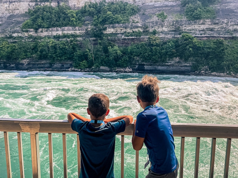 Two boys looking at the rapids on the Niagara River from the boardwalk of the Niagara White Water Walk.