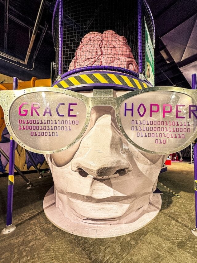 Large head sculpture wearing sunglasses that say Grace Hopper and a brain sticking out of the top of the head located inside of the Omaha Children's Museum.