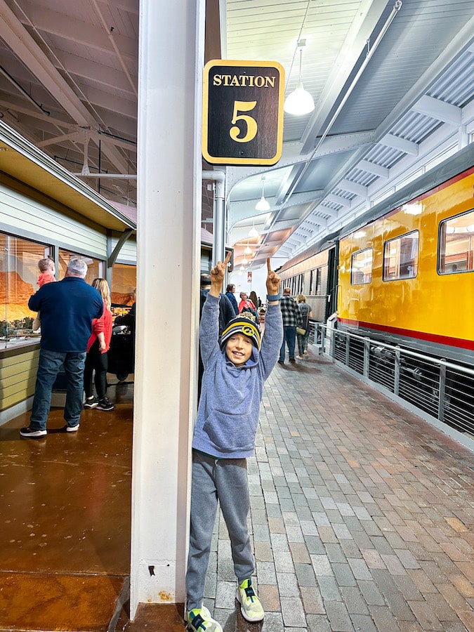 Boy wearing a stocking hat standing under a sign for station 5 at the Durham Museum in Omaha, Nebraska