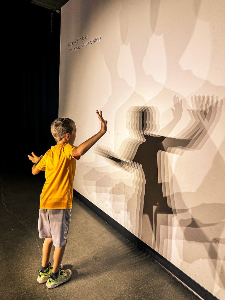 Boy facing a wall viewing his shadow at the Kiewit Luminarium in Omaha.