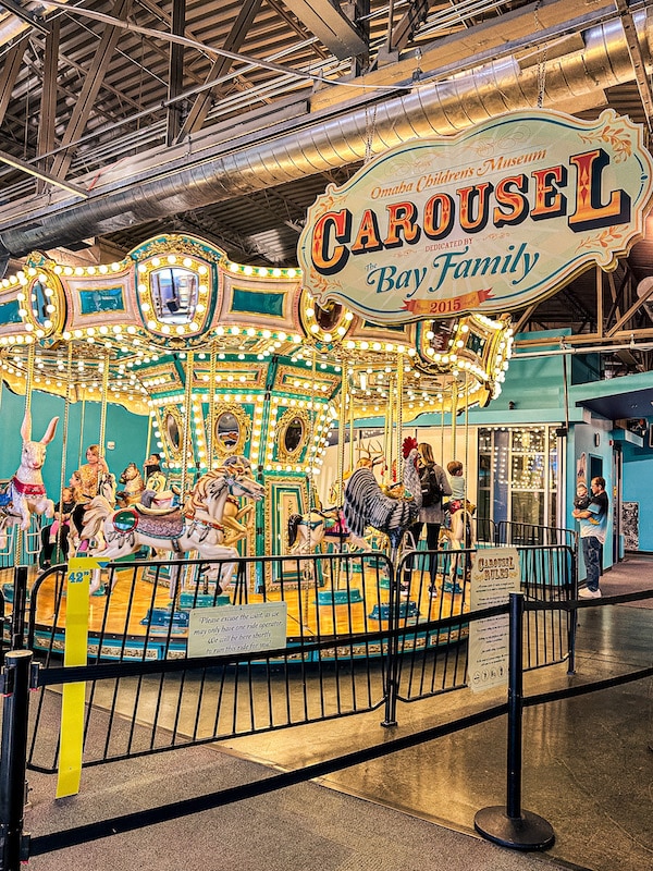 Bay Familly Carousel sign and carousel with a black fence around it.