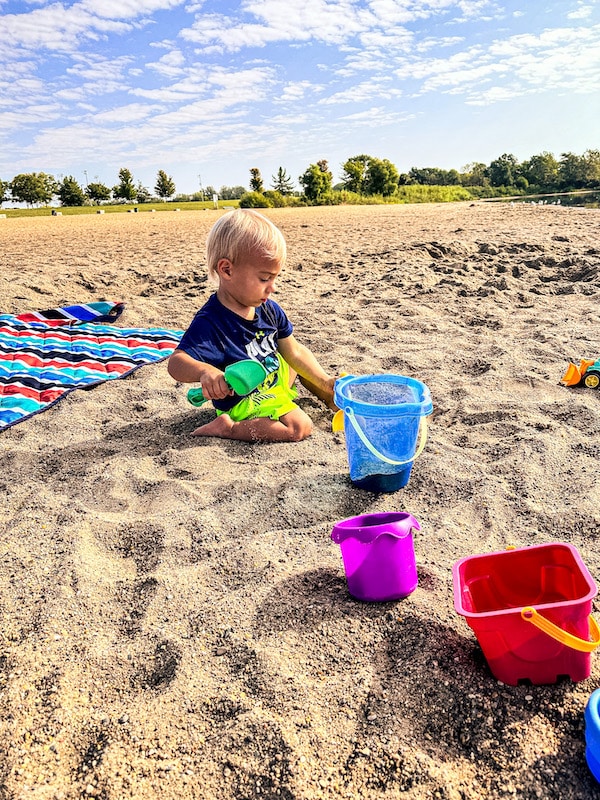 Small child playing in the sand with his sand toys at the beach at Raccoon River Park.