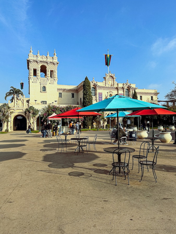 Tables and chairs with different colored umbrellas at the Balboa Park Plaza.