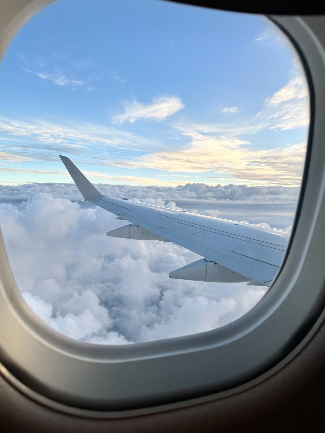 View of clouds and airplane wing out the airplane window.