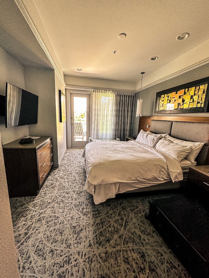 Master bedroom with king size bed plus flat screen tv hanging on the wall and door going out to the balcony