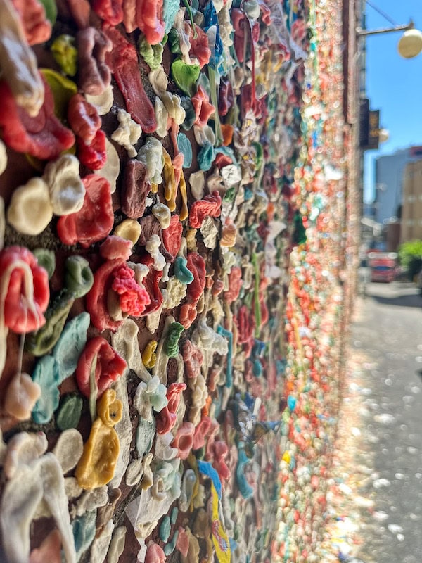 A close-up view of Seattle’s Gum Wall, covered in thick layers of colorful chewing gum pieces in various shapes and sizes.