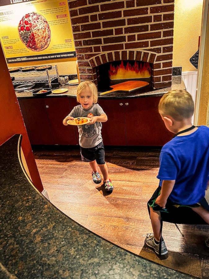 Child pretending to serve pizza in the pizza parlor play area inside the Children’s Village at The Magic House in St. Louis.