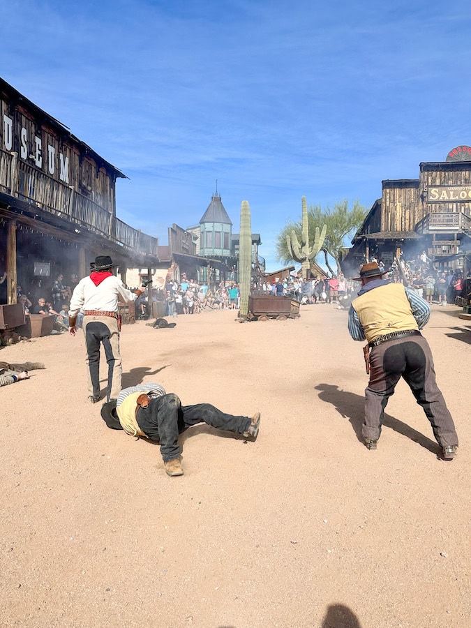 Old West gun fight show at Goldfield Ghost Town with performers and crowd watching in the background.
