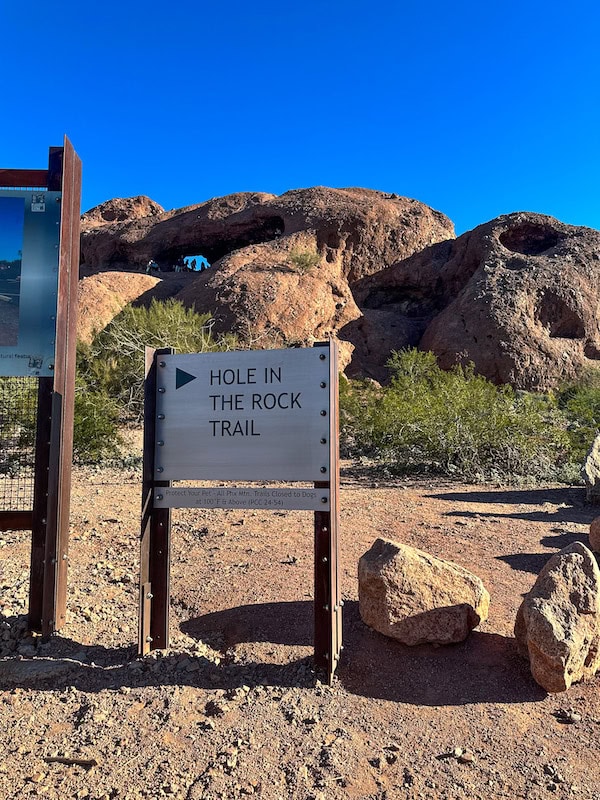 Hole in the Rock Trail sign with the rock formation in the background.