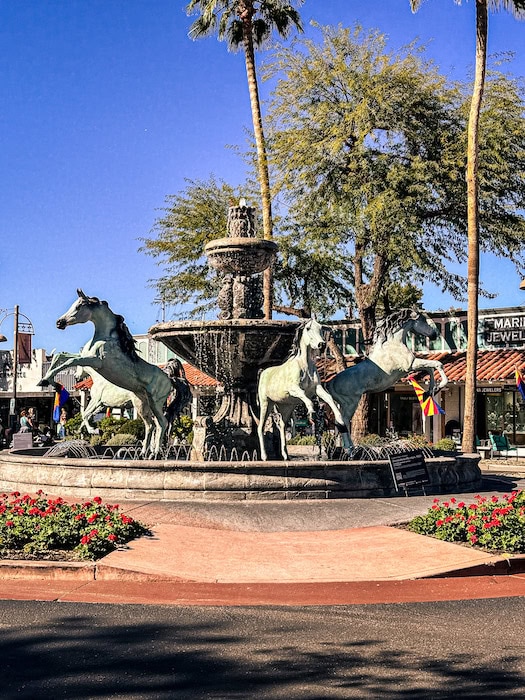 Horse fountain in Old Town Scottsdale, Arizona with palm trees and shops in the background.