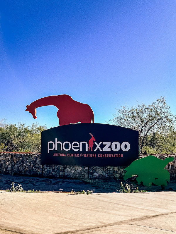 Phoenix Zoo sign with animal silhouettes against a bright blue sky in Phoenix, Arizona.