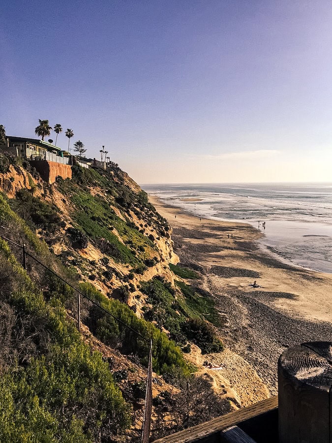 View from Sunset Cliffs in San Diego overlooking ocean waves, sandy beach, and coastal bluffs at sunset
