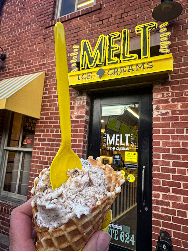 Hand holding a waffle cone with ice cream in front of MELT Ice Cream storefront in the Fort Worth Stockyards area