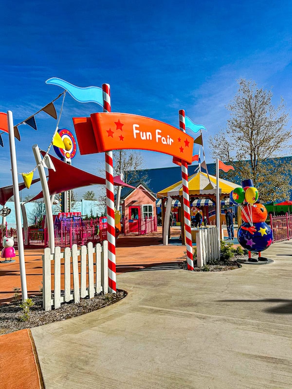 Colorful Fun Fair area at Peppa Pig Theme Park featuring play structures, flags, and bright signage in North Richland Hills, Texas