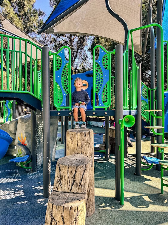 Young child sitting on playground equipment at Lake Hollywood Park in Los Angeles, California.