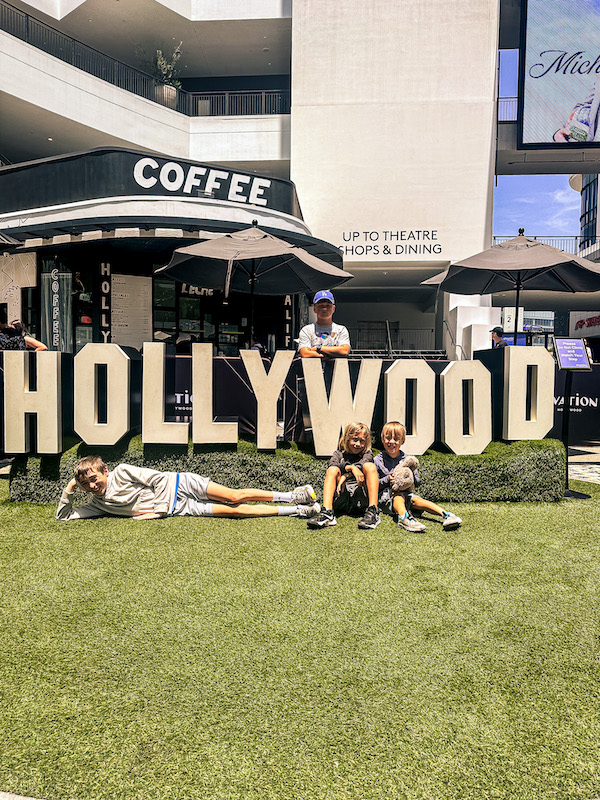 Four boys posing in front of a Hollywood sign display at Ovation Hollywood on Hollywood Boulevard.