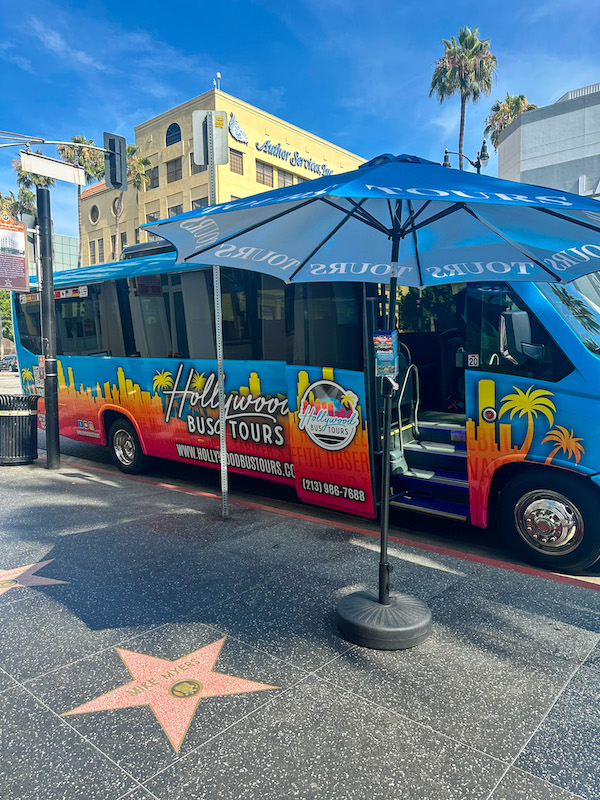 Hollywood Bus Tours vehicle parked along Hollywood Boulevard near the Hollywood Walk of Fame in Los Angeles.