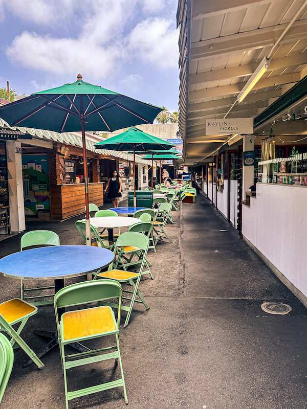Outdoor seating area surrounded by small restaurants and food vendors at the Original Farmers Market in Los Angeles.