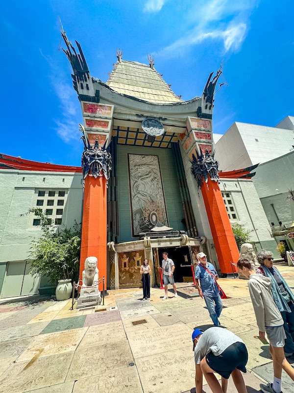 TCL Chinese Theatre on Hollywood Boulevard in Los Angeles with visitors walking among the famous celebrity handprints and footprints in the forecourt.