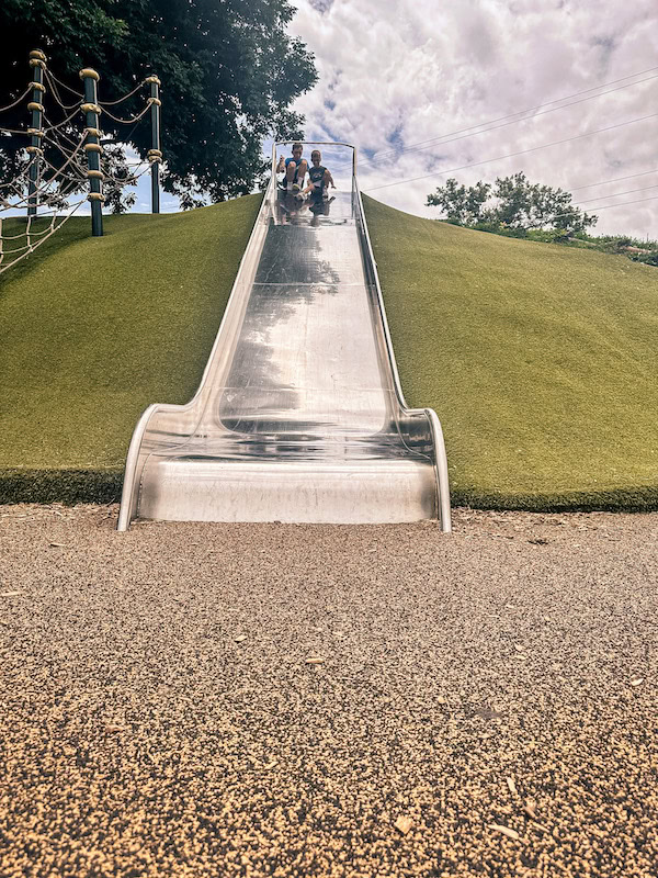 Children getting ready to race down the large stainless steel hill slide at Walker Johnston Park in Urbandale, Iowa.