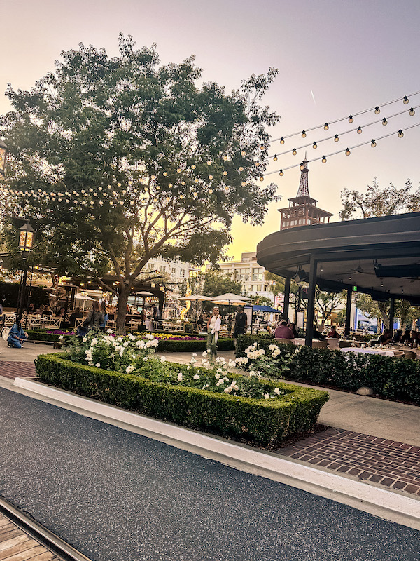 The Americana at Brand in Glendale, California, with outdoor dining, string lights, and landscaped gardens at sunset.