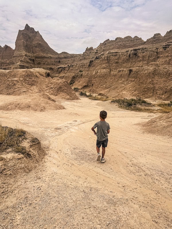 Young child walking through the rugged rock formations and sandy trails in Badlands National Park, South Dakota.