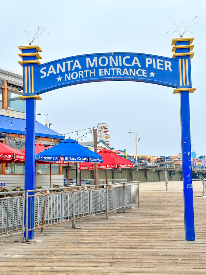 Santa Monica Pier North Entrance sign with the pier, Ferris wheel, and boardwalk in Santa Monica, California.