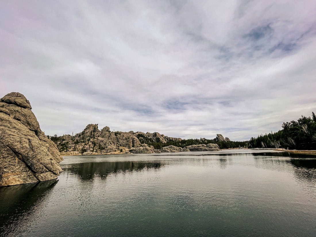 Panoramic view of Sylvan Lake surrounded by granite rock formations in Custer State Park, South Dakota.