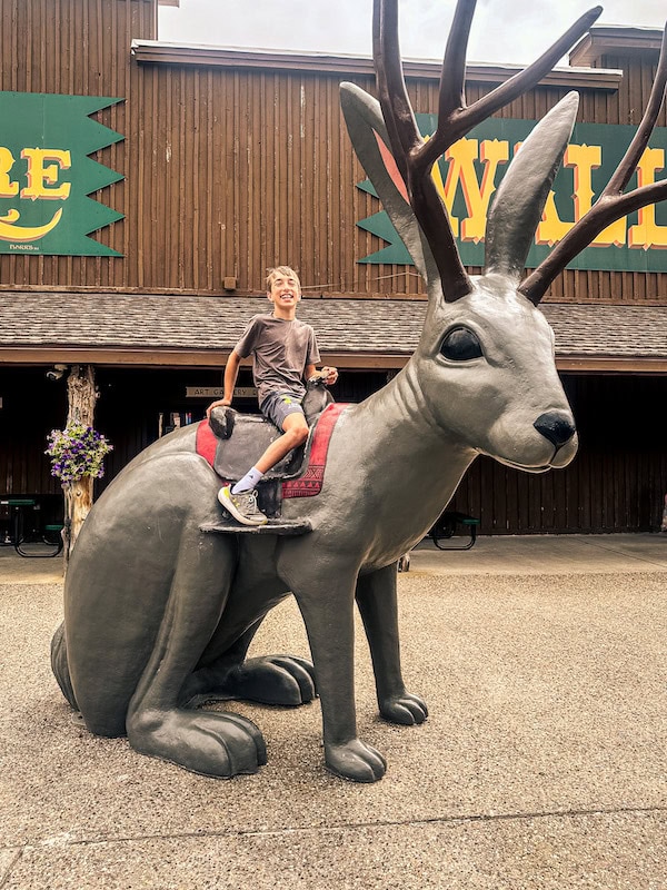 Child riding the giant jackalope statue outside Wall Drug in Wall, South Dakota.