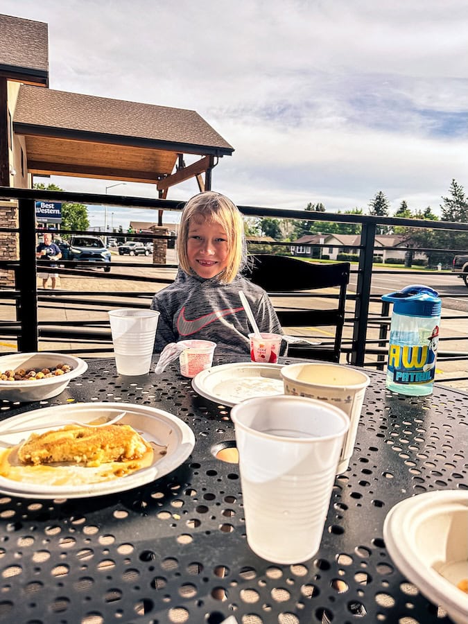 Child smiling and eating breakfast outside on the patio at Best Western Sunset Inn in Cody, Wyoming.