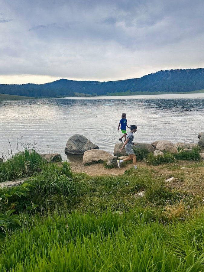 Two boys exploring the rocky shoreline of Meadowlark Lake in Wyoming's Bighorn Mountains.