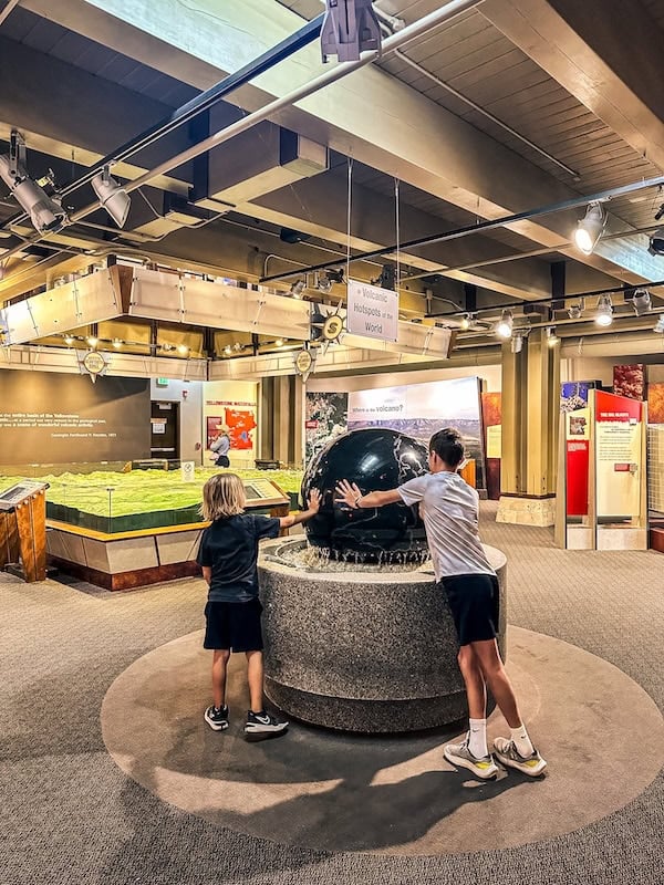 Children exploring the large rotating globe exhibit inside the Canyon Visitor Education Center in Yellowstone National Park.