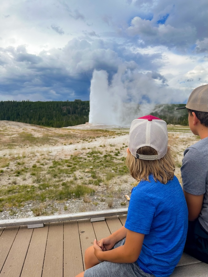 Children watching Old Faithful erupt from the viewing area in Yellowstone National Park.