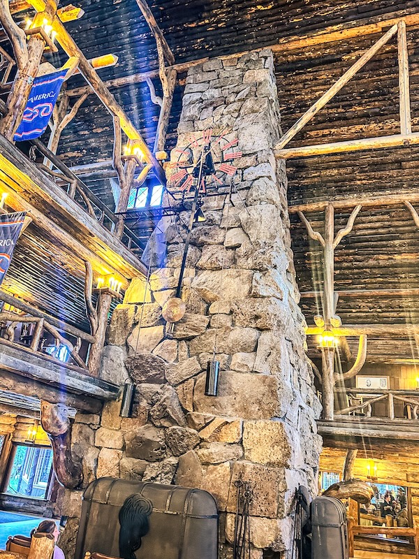 Interior of Old Faithful Inn featuring the massive stone fireplace and rustic log architecture in Yellowstone National Park.