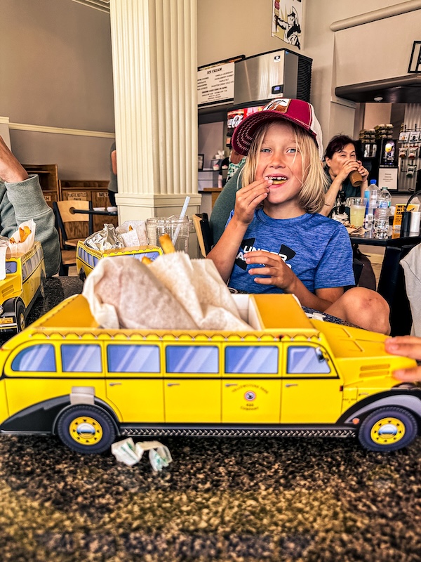 Child eating lunch with a yellow Yellowstone bus kids meal container at Terrace Grill near Mammoth Hot Springs.