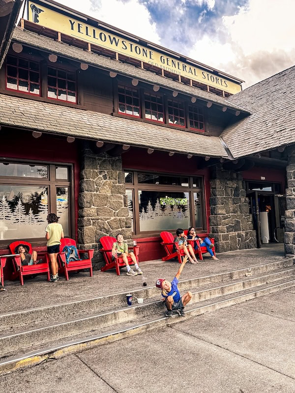Yellowstone General Store near Old Faithful with visitors relaxing in red Adirondack chairs outside.